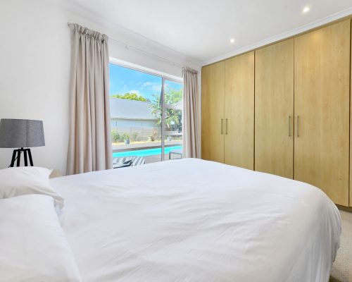 Luxury Beach Holiday Accommodation in Sunset Beach, Cape Town Spacious bedroom with built in wardrobes and pool view at sunset beach house luxury holiday accommodation Cape Town