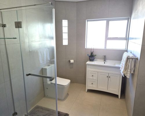 Luxury Beach Holiday Accommodation in Sunset Beach, Cape Town Modern bathroom with a walk-in glass shower, elegant vanity and premium finishes at The Sunset Beach House in Sunset Beach, Cape Town.